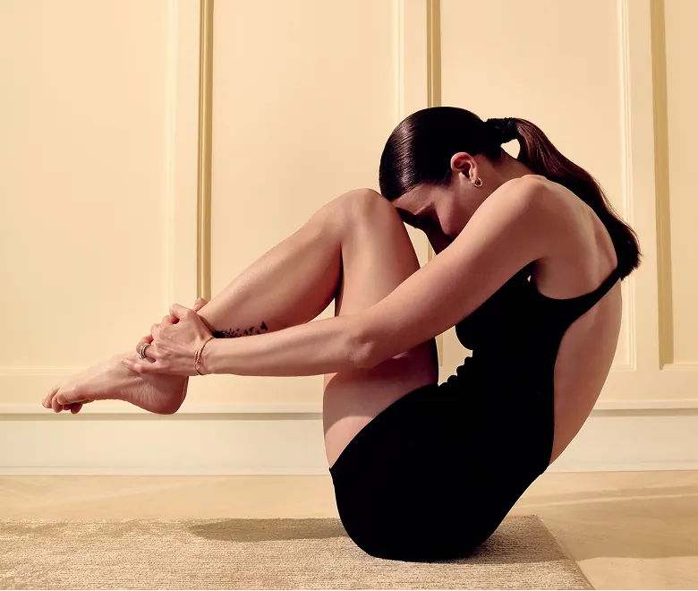Donna in body nero che esegue una posizione di Pilates Linfodrenante per l’attivazione linfatica e la riduzione della cellulite