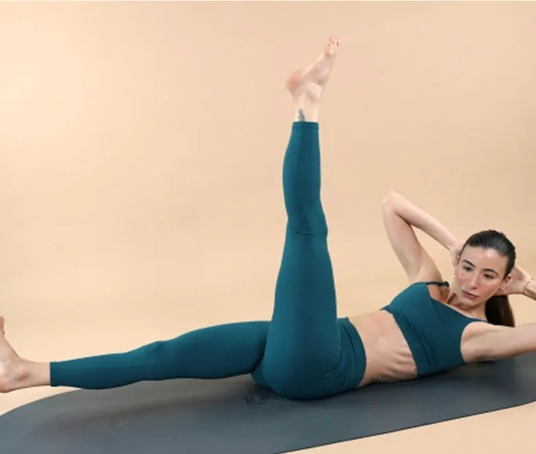 Donna in abbigliamento sportivo color petrolio che esegue un esercizio di Pilates per gli obliqui per scolpire e rimodellare il corpo